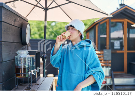 サウナから出て水分補給する男性 126510117