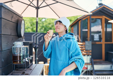 サウナから出て水分補給する男性 126510118