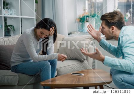 Couple arguing at home, woman covering face while man gestures emotionally 126511813