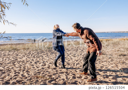 Loving couple walks on beach along sea on sunny autumn day. Weekend and lifestyle concept. High quality photo Loving couple walks on beach along sea on sunny autumn day. Weekend and lifestyle concept. High quality photo 126515504