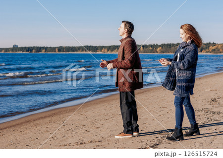 Loving couple walks on beach along sea on sunny autumn day. Weekend and lifestyle concept. High quality photo Loving couple walks on beach along sea on sunny autumn day. Weekend and lifestyle concept. High quality photo 126515724