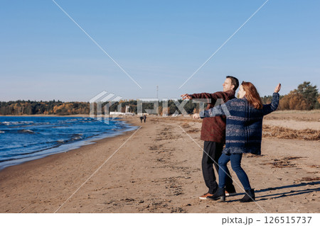 Young carefree couple in love throwing pebbles, shells, stones into sea outdoors. Fun family game together. High quality photo 126515737