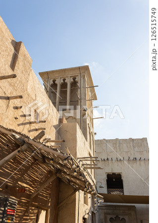 Old town in Al Seef Cultural Historical District on shores of Dubai Creek. Tourist place with old streets, houses and shops, Dubai, UAE. Vertical photo 126515749