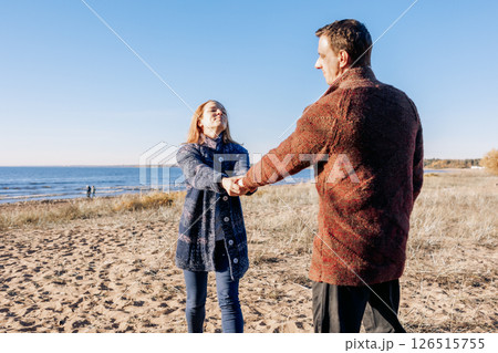 Loving couple walks on beach along sea on sunny autumn day. Weekend and lifestyle concept. High quality photo Loving couple walks on beach along sea on sunny autumn day. Weekend and lifestyle concept. High quality photo 126515755