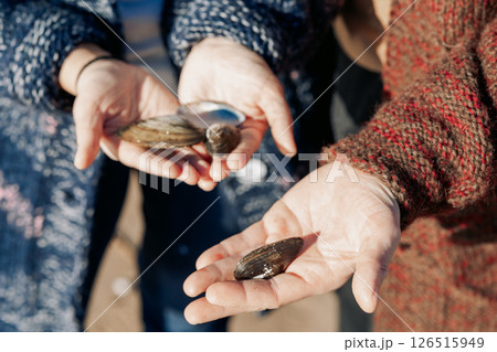 Seashells in hands, close-up. Young carefree couple in love throwing pebbles, shells, stones into sea outdoors. Fun family game together. High quality photo Seashells in hands, close-up. Young carefree couple in love throwing pebbles, shells, stones into sea outdoors. Fun family game together. High quality photo 126515949
