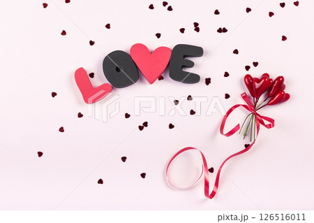 Valentine's day romantic party concept. Gift word LOVE and bouquet of sweet hearts decorations on pink background. Top view, flat lay, copy space Valentine's day romantic party concept. Gift word LOVE and bouquet of sweet hearts decorations on pink background. Top view, flat lay, copy space 126516011