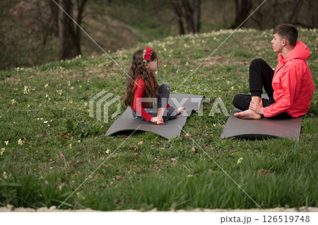 Outdoor yoga practice brings peace and connection between a child and an adult surrounded by nature on a spring afternoon, creating a serene atmosphere and joyful bond Outdoor yoga practice brings peace and connection between a child and an adult surrounded by nature on a spring afternoon, creating a serene atmosphere and joyful bond 126519748