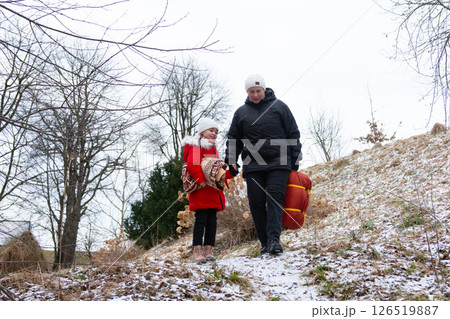 Winter adventure in a snowy landscape with a parent and child exploring nature while carrying supplies for a cozy day outdoors 126519887