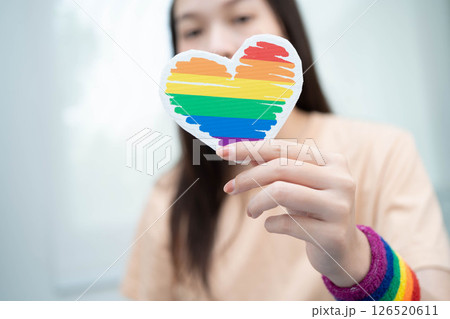 Asian woman holding LGBT heart with rainbow flag. 126520611