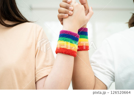 Asian LGBT couple woman holding hand wearing rainbow wristband. 126520664