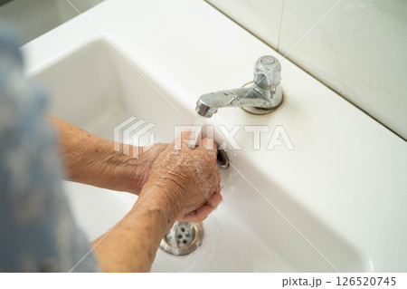 Asian elderly woman washing hands in bathroom. 126520745