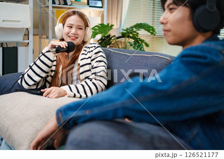 Podcast conversation between young man and woman with headphones and microphones 126521177