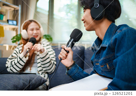 Young man speaking in podcast with headphones and microphone at home 126521201