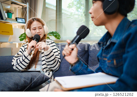 Podcast conversation between young man and woman with headphones and microphones 126521202