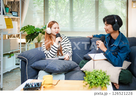 Two young people recording podcast at home with headphones and microphones 126521228