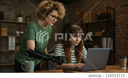 Woman with bionic arm helping coder colleague with laptop in the office 126523115