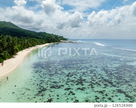 Serene sandy shore and calm azure water with a coral reef. Anse Marie Louise, Seychelles, Mahe. 126526980