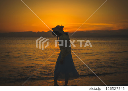 夕焼けの海辺を散策する女性 夕焼けの海辺を散策する女性 126527243