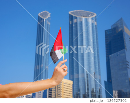 female hand holding tiny flag of UAE 126527502