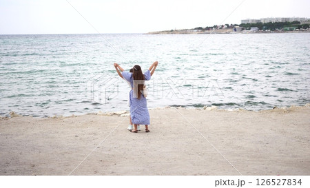 Woman Beach Sea Malta: Joyful woman in dress celebrating at Malta seaside, arms raised, peaceful ocean view. Woman Beach Sea Malta: Joyful woman in dress celebrating at Malta seaside, arms raised, peaceful ocean view. 126527834