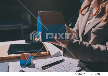 Female Real Estate Broker presenting and advised to model home and building project detail in the office, sign purchase sales contract, agreements concerned mortgage loan offer and insurance. 126528335