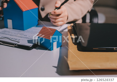 Female Real Estate Broker presenting and advised to model home and building project detail in the office, sign purchase sales contract, agreements concerned mortgage loan offer and insurance. 126528337