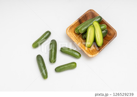 木の小皿に乗ったミニキュウリ　白背景とちいさな胡瓜の素材写真 126529239