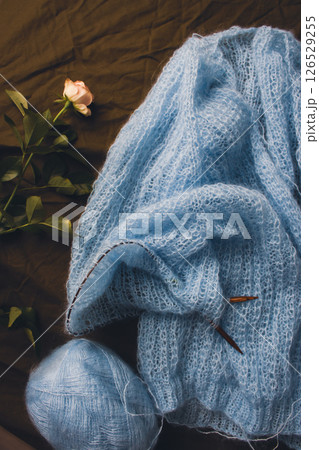 Blue cotton knitting with knitting needles and tiny rose. Soft blue knitwear with wooden circle needles and flower on bed. Knitting lifestyle. Cozy hobby. Craft product concept. Elegant lifestyle. Blue cotton knitting with knitting needles and tiny rose. Soft blue knitwear with wooden circle needles and flower on bed. Knitting lifestyle. Cozy hobby. Craft product concept. Elegant lifestyle. 126529255