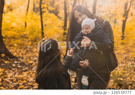 Mother holds baby in autumn forest. Family bonding and emotional connection through touch and nature 126530777