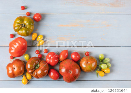 Red, green, yellow and striped tomatoes on blue wooden table. Flat lay. Healthy food, fresh healthy vegetables from the garden Red, green, yellow and striped tomatoes on blue wooden table. Flat lay. Healthy food, fresh healthy vegetables from the garden 126531644