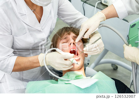 Teenager receiving dental treatment in modern clinic during daytime Teenager receiving dental treatment in modern clinic during daytime 126532007