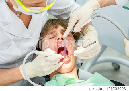 Dental procedure during an examination with a young patient in a modern clinic setting Dental procedure during an examination with a young patient in a modern clinic setting 126532008