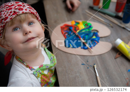 A child is engaged in the creative activity of painting using vibrant and colorful hues A child is engaged in the creative activity of painting using vibrant and colorful hues 126532174