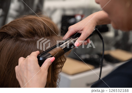 The Art of Styling Hair with a Flat Iron in a Professional Salon Setting for Clients 126532188