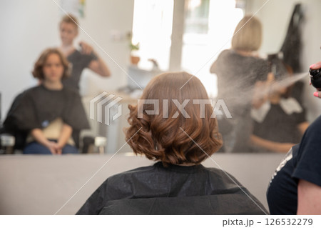 A woman is receiving a trendy haircut at a chic, modern salon from a professional beautician A woman is receiving a trendy haircut at a chic, modern salon from a professional beautician 126532279