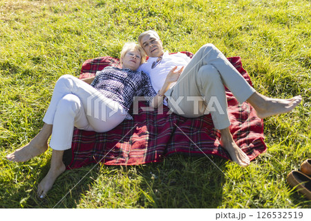 Senior couple relaxing on blanket in meadow, enjoying sunny day 126532519