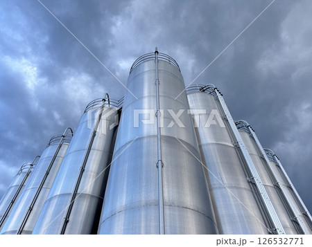 Large stack of silvery tanks with a cloudy sky in the background Large stack of silvery tanks with a cloudy sky in the background 126532771