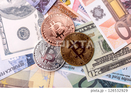 Round metal bitcoin on a background of paper banknotes of different currencies Round metal bitcoin on a background of paper banknotes of different currencies 126532929