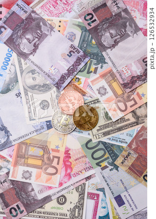 Round metal bitcoin on a background of paper banknotes of different currencies Round metal bitcoin on a background of paper banknotes of different currencies 126532934