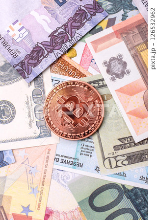 Round metal bitcoin on a background of paper banknotes of different currencies 126532962