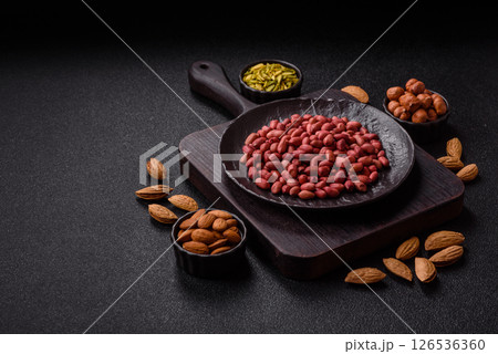 Peanuts or peeled graundnut in a bowl on a dark concrete background Peanuts or peeled graundnut in a bowl on a dark concrete background 126536360