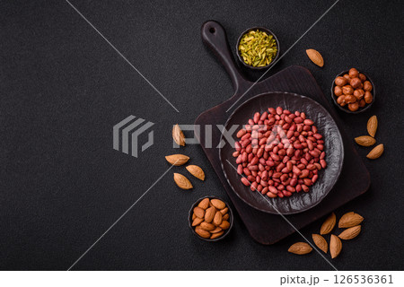 Peanuts or peeled graundnut in a bowl on a dark concrete background Peanuts or peeled graundnut in a bowl on a dark concrete background 126536361