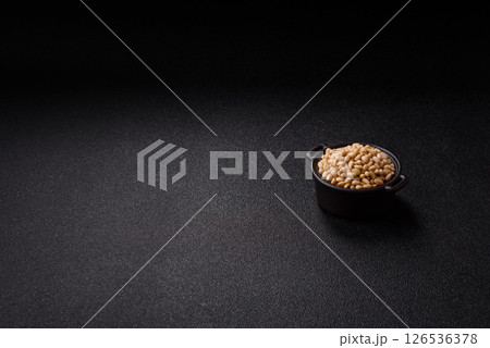 Peeled pine nuts in a bowl on a dark concrete background 126536378
