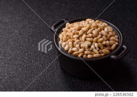 Peeled pine nuts in a bowl on a dark concrete background Peeled pine nuts in a bowl on a dark concrete background 126536382