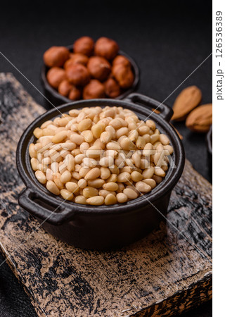 Peeled pine nuts in a bowl on a dark concrete background 126536389