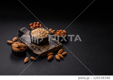 Peeled pine nuts in a bowl on a dark concrete background Peeled pine nuts in a bowl on a dark concrete background 126536390