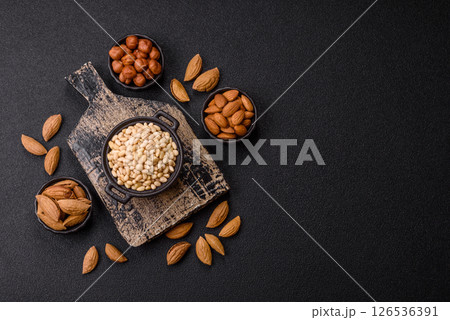 Peeled pine nuts in a bowl on a dark concrete background Peeled pine nuts in a bowl on a dark concrete background 126536391
