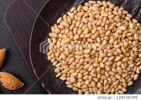 Peeled pine nuts in a bowl on a dark concrete background 126536399