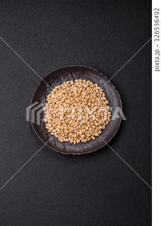 Peeled pine nuts in a bowl on a dark concrete background 126536492