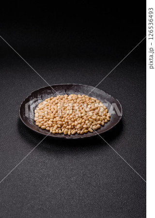 Peeled pine nuts in a bowl on a dark concrete background 126536493